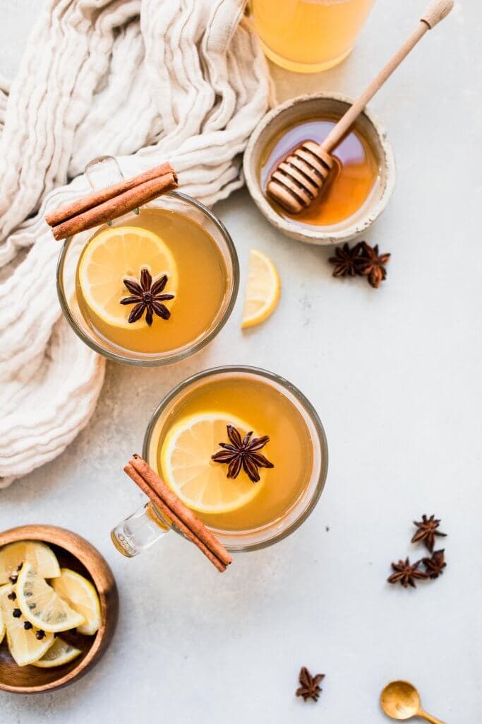 Overhead shot of three hot toddies next to bowl of honey.