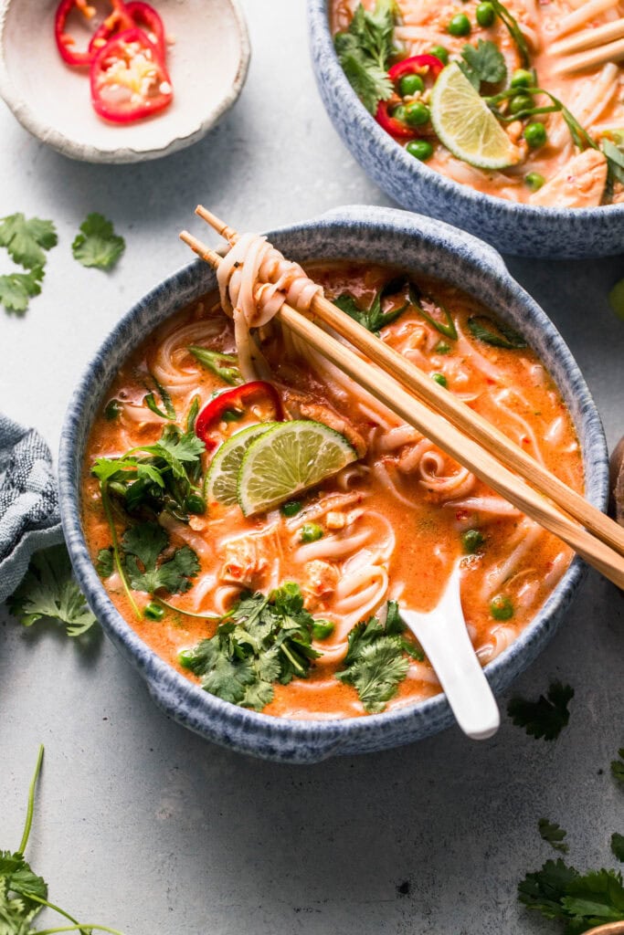 Thai chicken noodle soup in bowl with chopsticks.