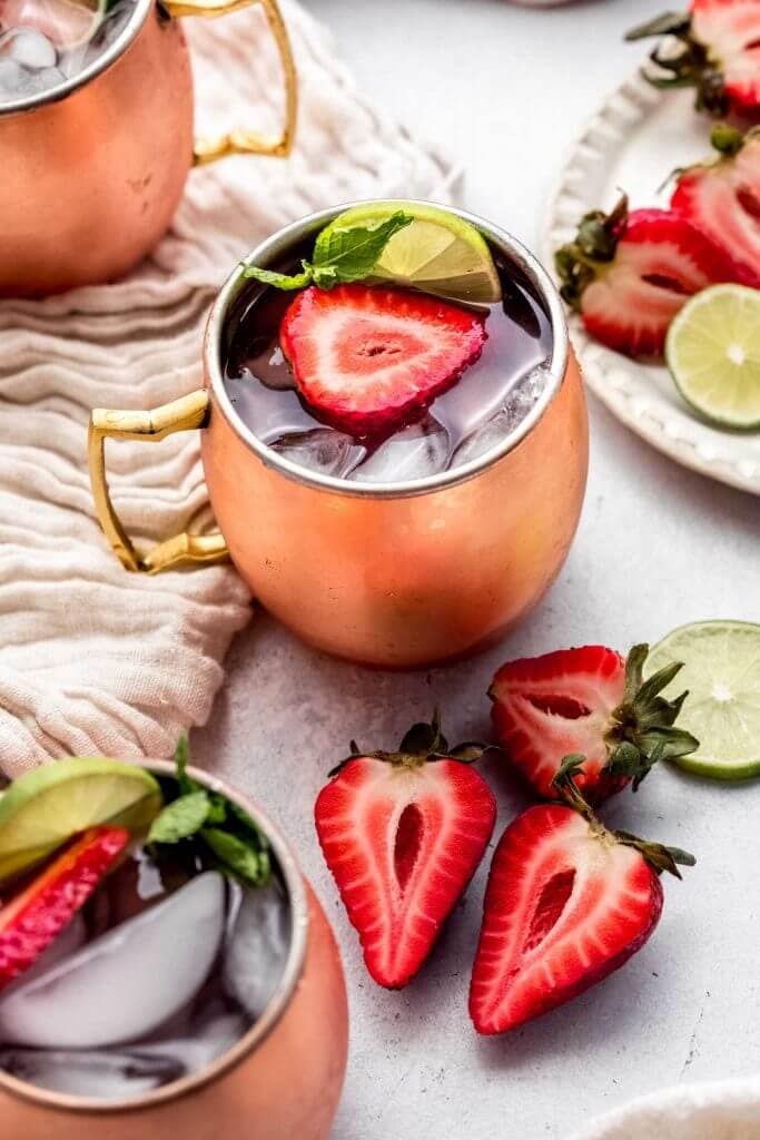 Side view of moscow mule with strawberries on counter. 