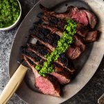 Grilled Rack of Lamb with Pistachio Basil Pesto will upgrade your next BBQ or tailgate. Frenched rack of lamb is grilled, sliced & topped with basil pesto. | platingsandpairings.com