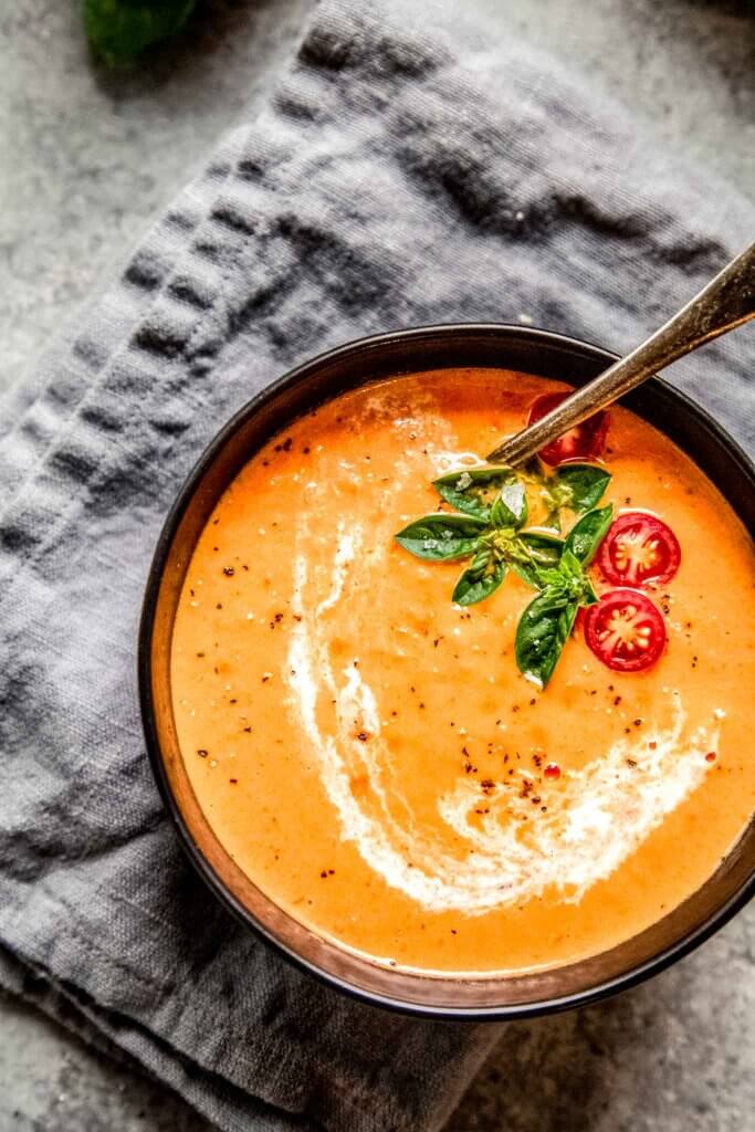 Bowl of tomato bisque next to bread.