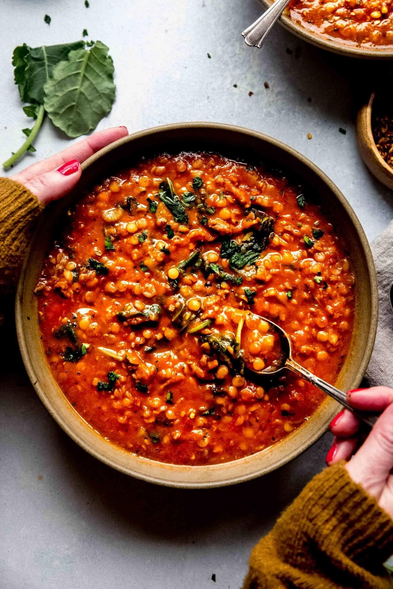 Hands holding bowl of instant pot lentil soup.