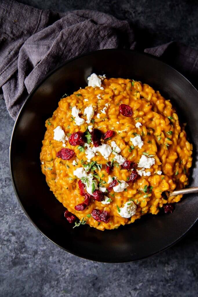 Pumpkin Risotto with Goat Cheese and Dried Cranberries in bowl - Close up shot.