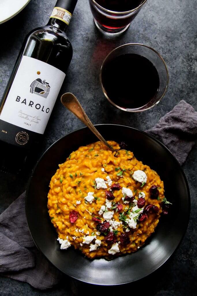 Pumpkin Risotto with Goat Cheese and Dried Cranberries in bowl with a Barolo wine pairing.