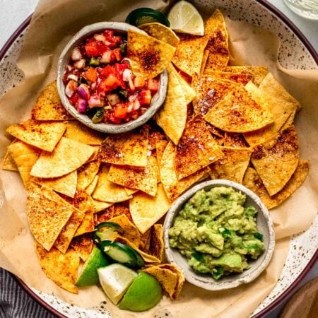 Baked tortilla chips in basket with guacamole and salsa.