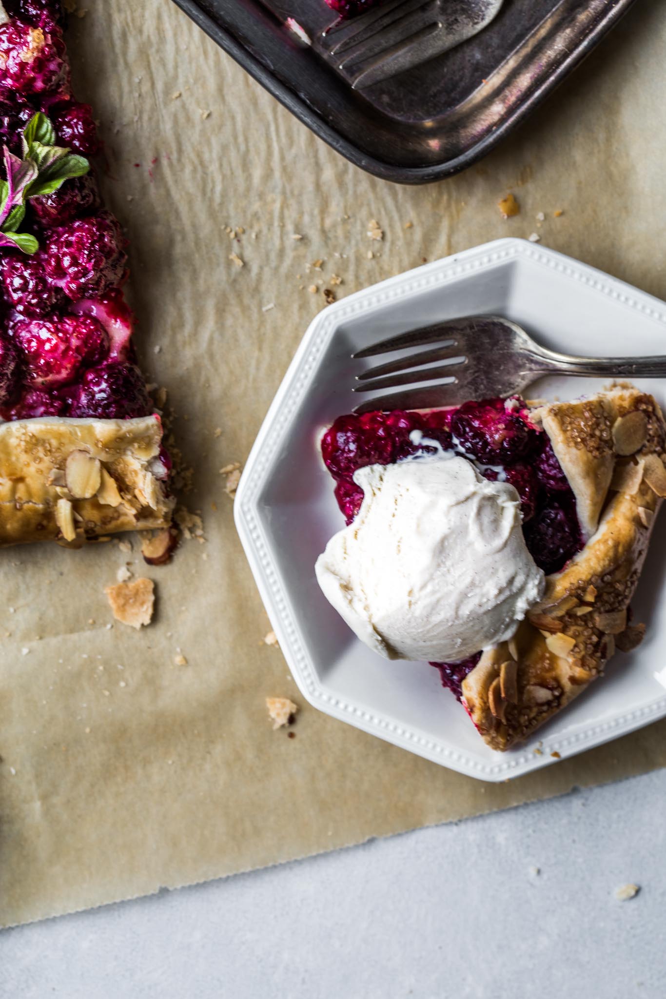 Piece of blackberry galette with scoop of ice cream.