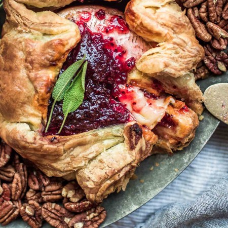 Overhead shot of baked brie in puff pastry with red currant fruit spread.