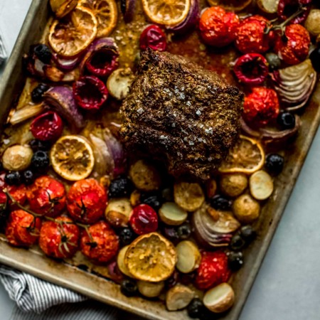 Veggies and olives arranged on sheet pan topped with lamb - out of oven.