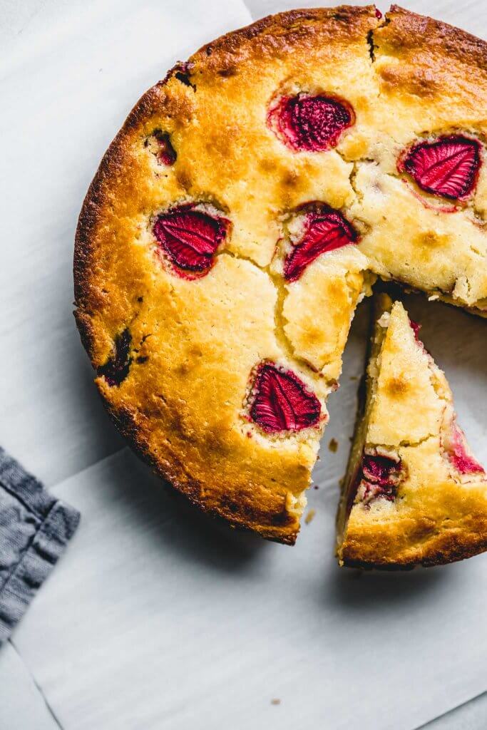 Overhead shot of strawberry ricotta cake with piece taken out.