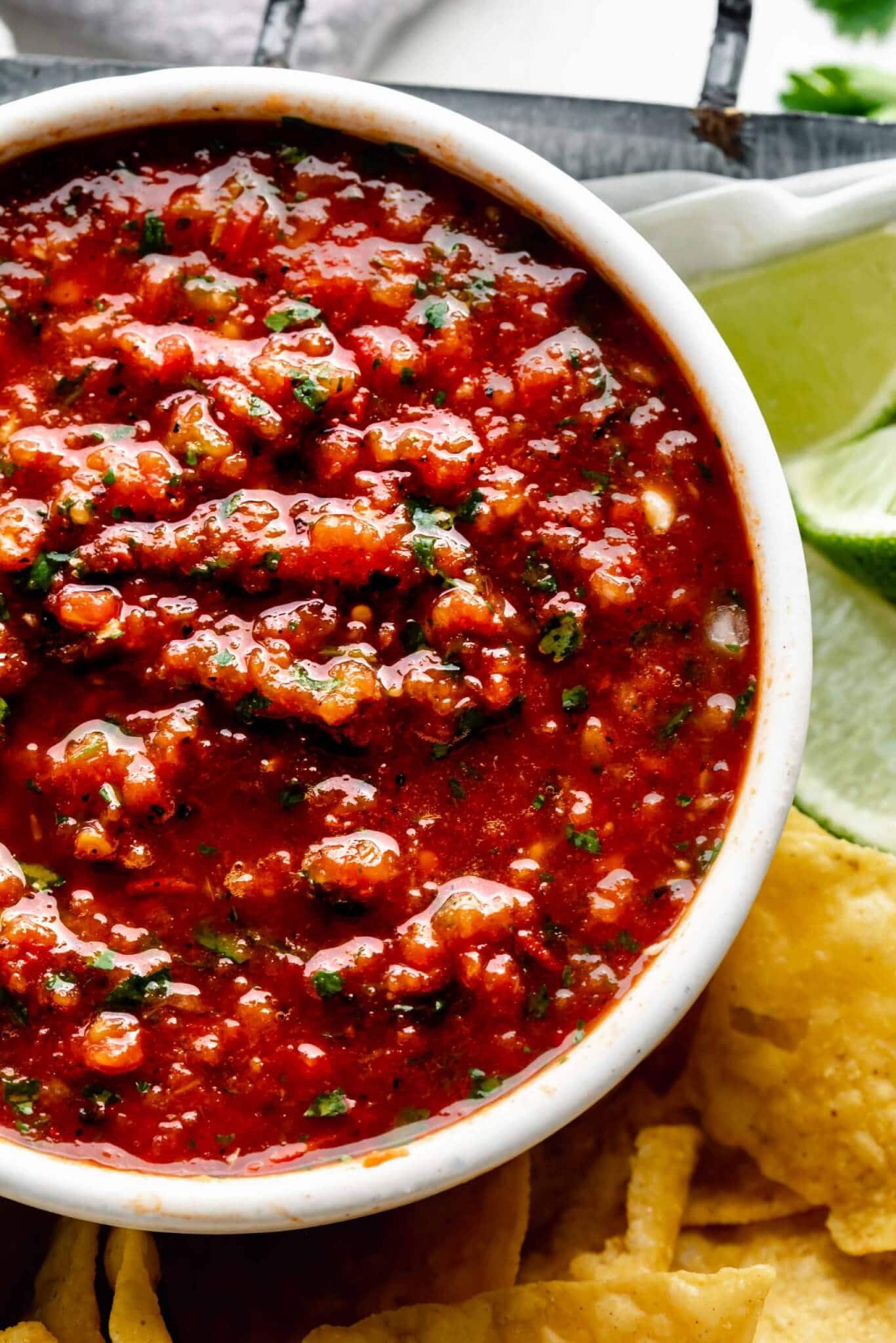 Bowl of chipotle salsa in serving tray with chips and limes.