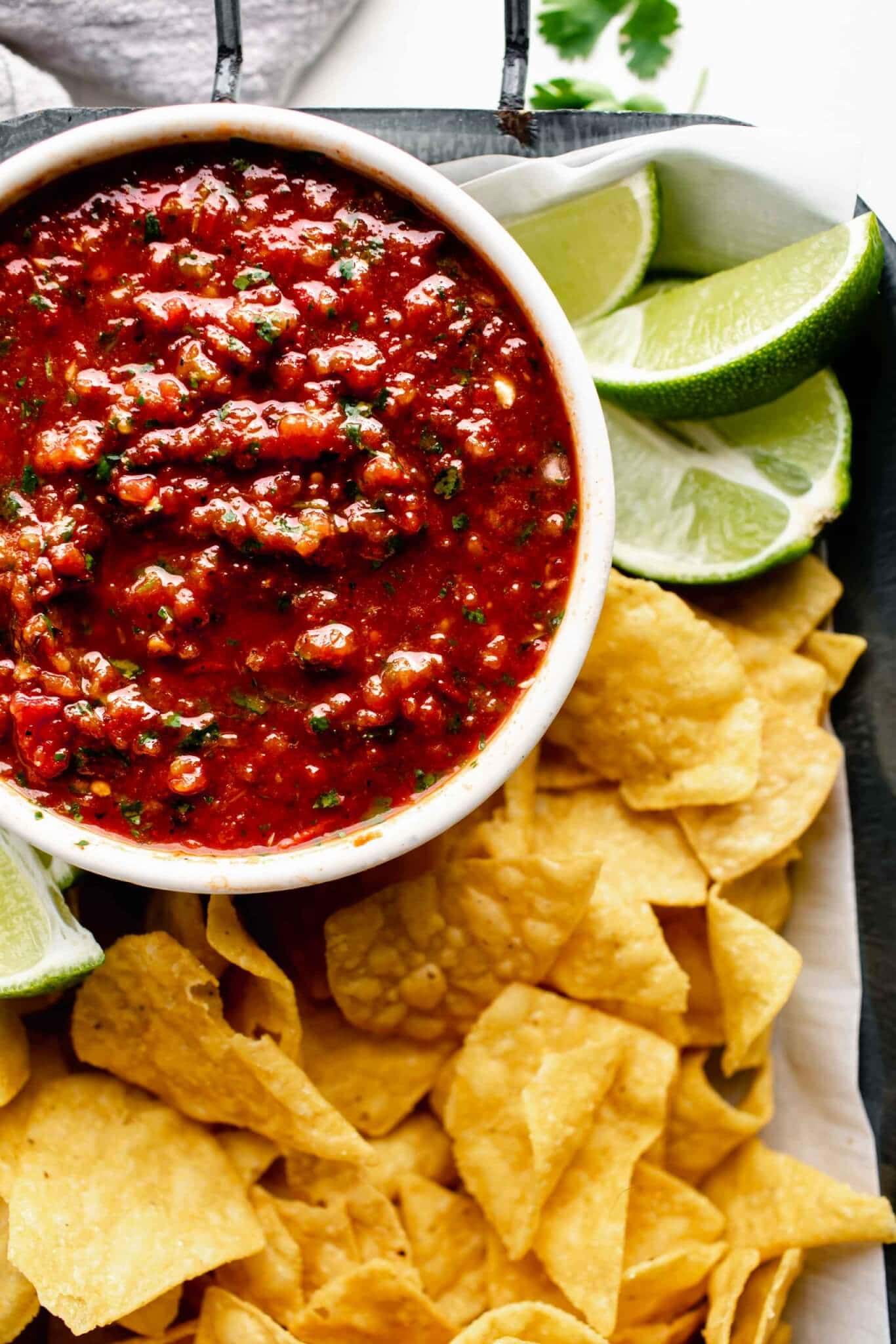 Bowl of chipotle salsa in serving tray with chips and limes. 