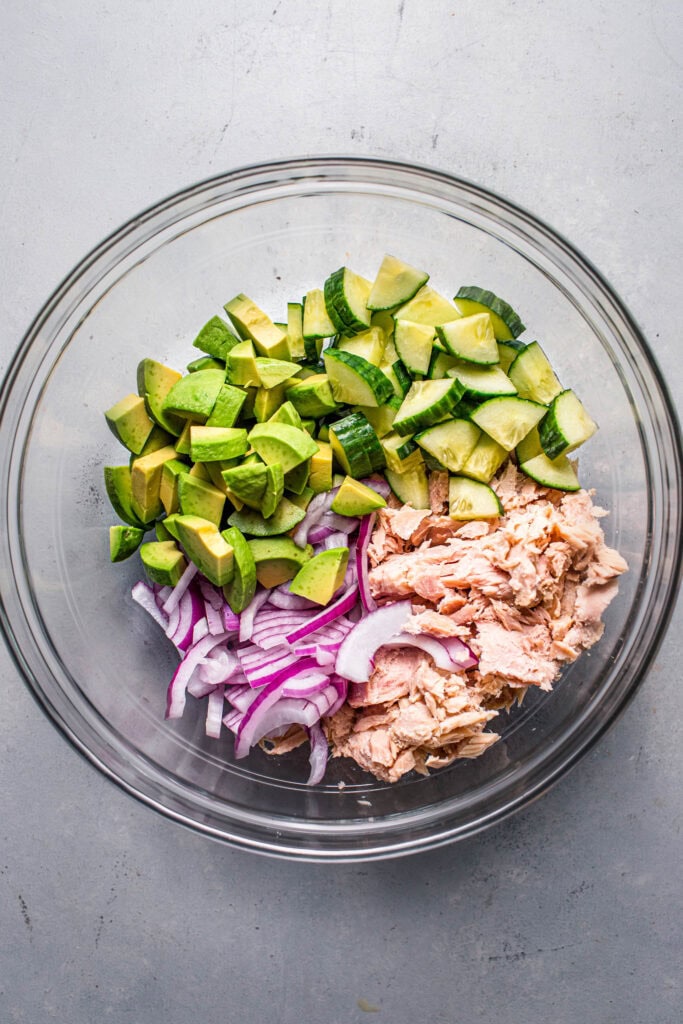 Avocado cucumber salad ingredients in bowl before tossing with dressing.
