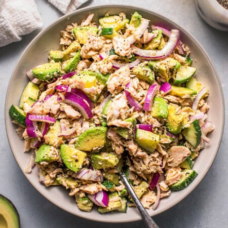 Overhead shot of avocado tuna salad in white bowl with serving spoon.
