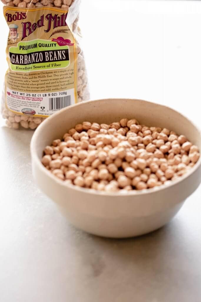 Bowl of dried chickpeas next to bag of Bob's Red Mill chickpeas.
