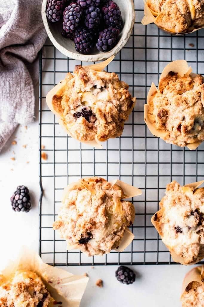 Overhead shot of blackberry muffins on cooling rack next to bowl of blackberries.