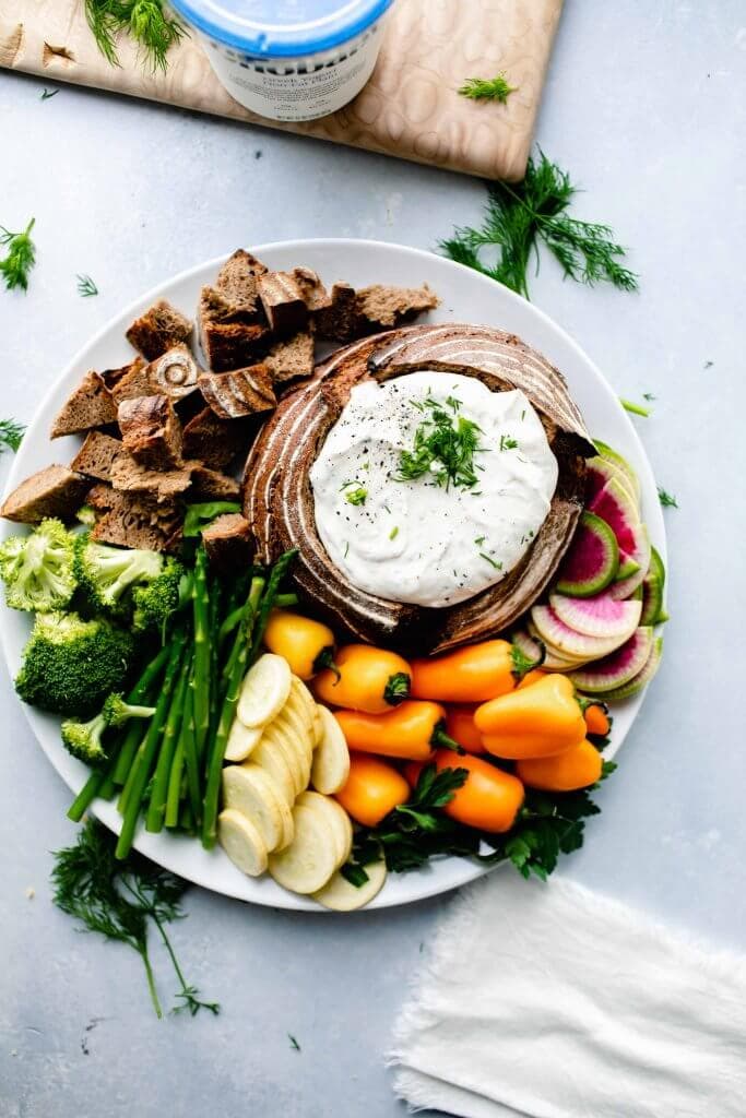 Overhead shot of ranch dip in bread bowl next to veggies.