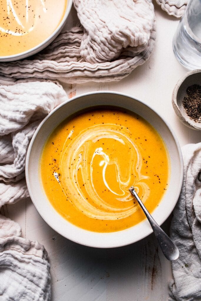 Bowl of curried butternut soup on counter with spoon. 