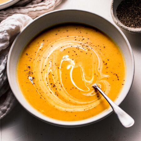 Side view of curried butternut squash soup in bowl with swirl of yogurt on top.