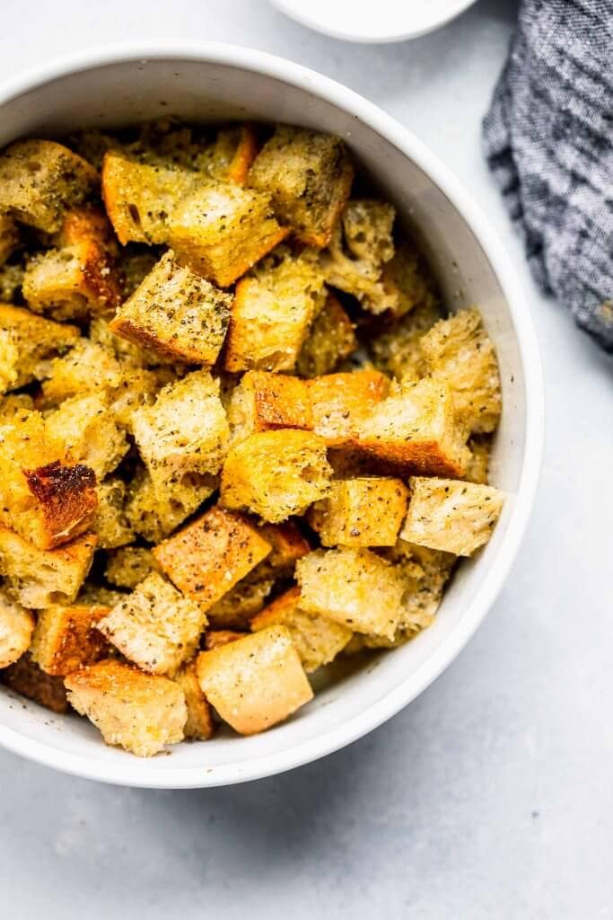 Bowl of cubes of bread tossed with olive oil.