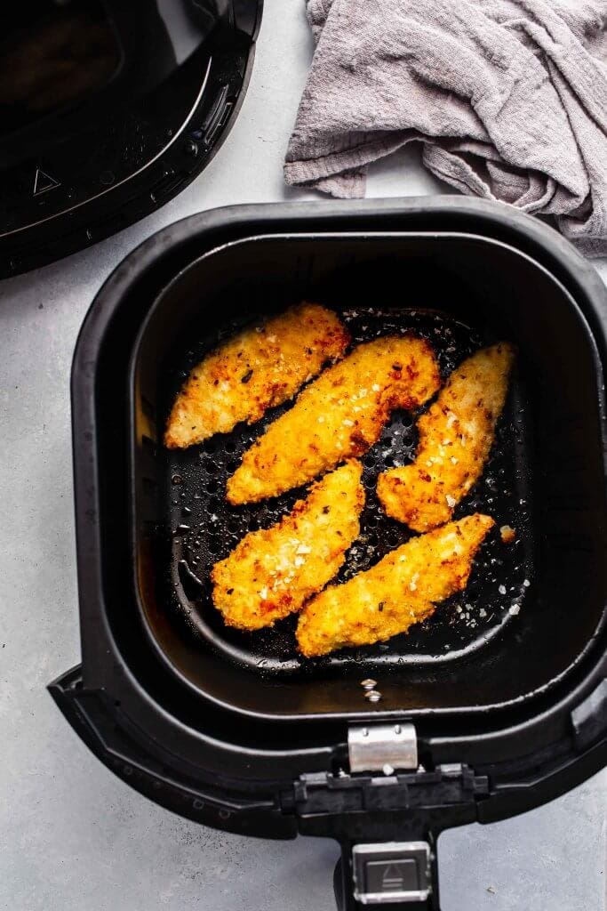 Chicken strips in air fryer basket.