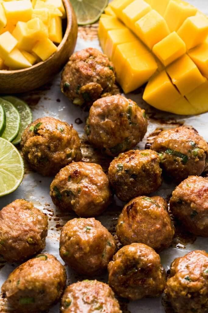 Meatballs on baking sheet next to mango.