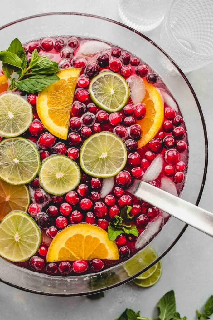 Christmas punch in bowl garnished with lime & orange slices, cranberries & mint sprigs.