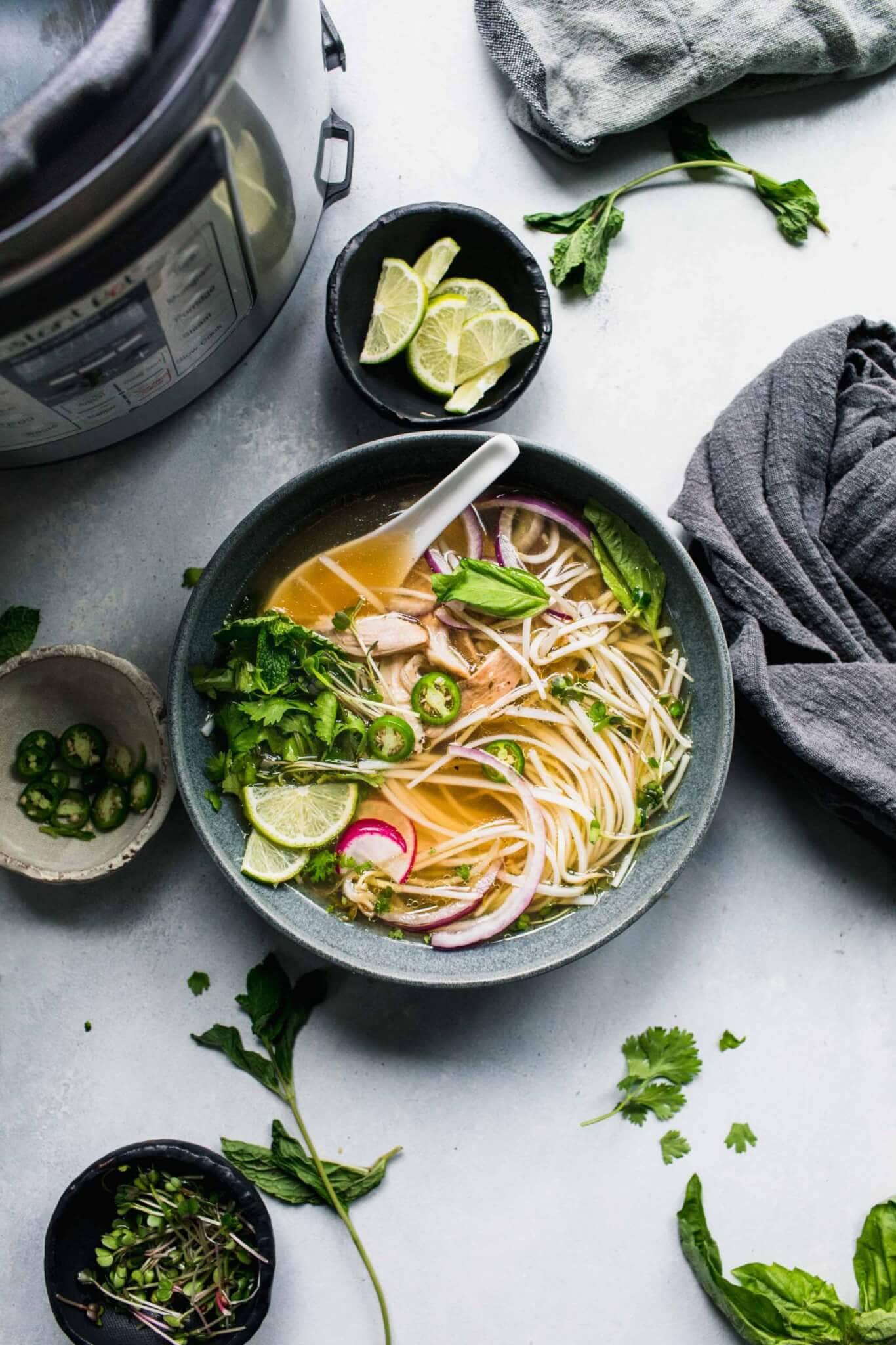 Bowl of pho next to instant pot. 