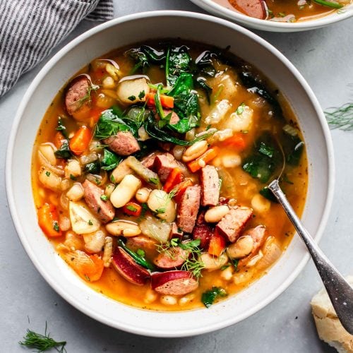 Overhead shot of two bowls of kielbasa soup on counter.