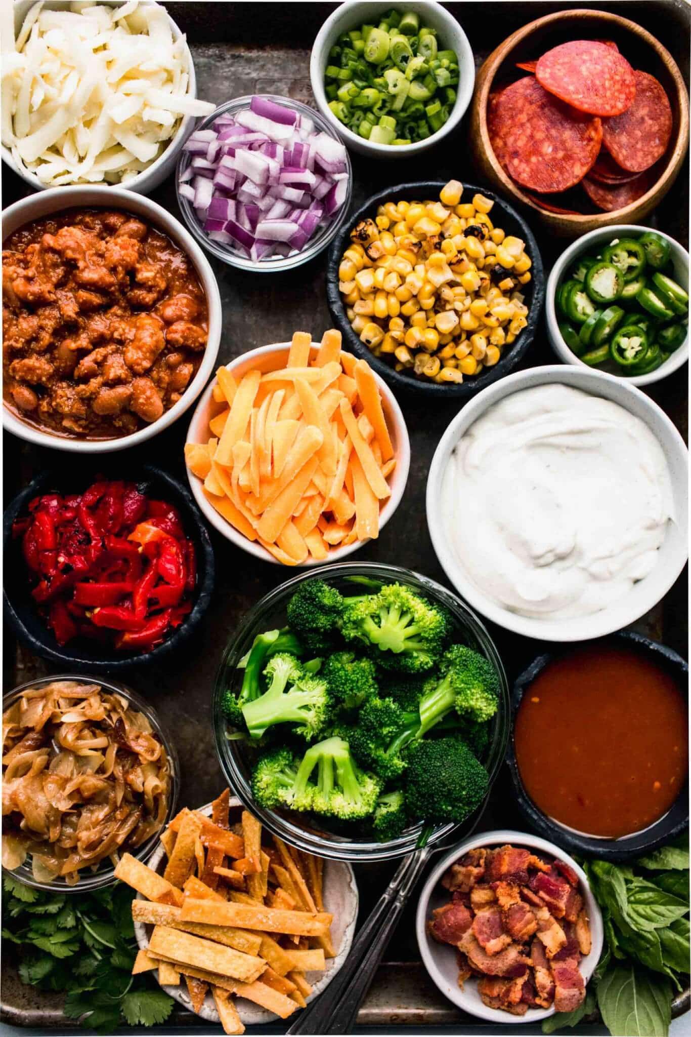 Toppings for baked potatoes in bowls on tray. 