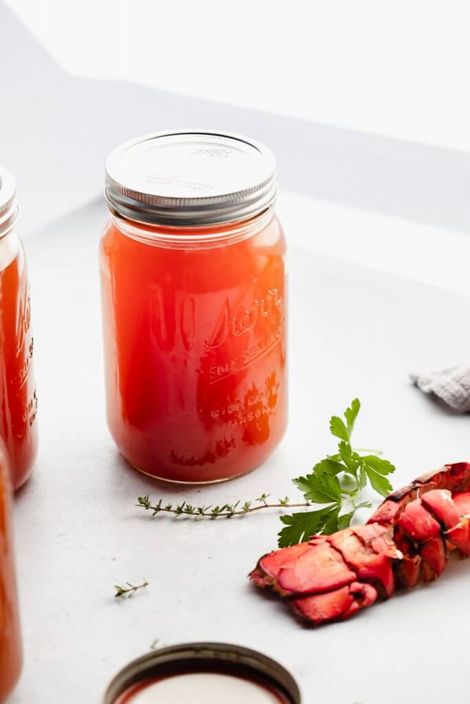 Jar of seafood stock on counter next to lobster tail.
