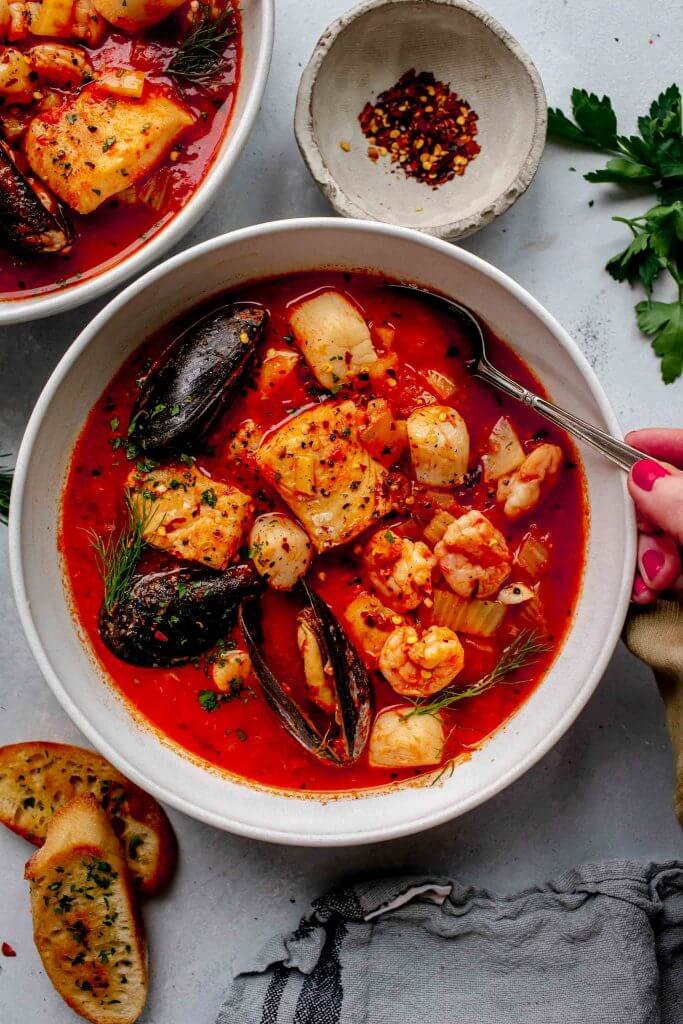 Overhead shot of cioppino in white bowl with spoon.