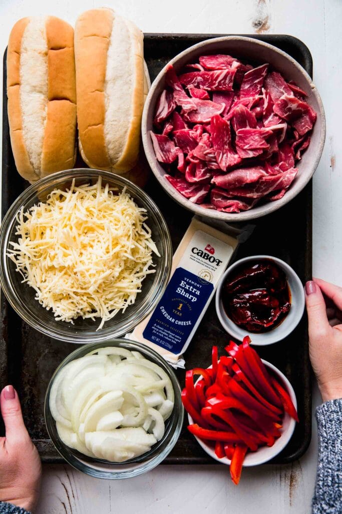 Ingredients for cheesesteaks on tray.