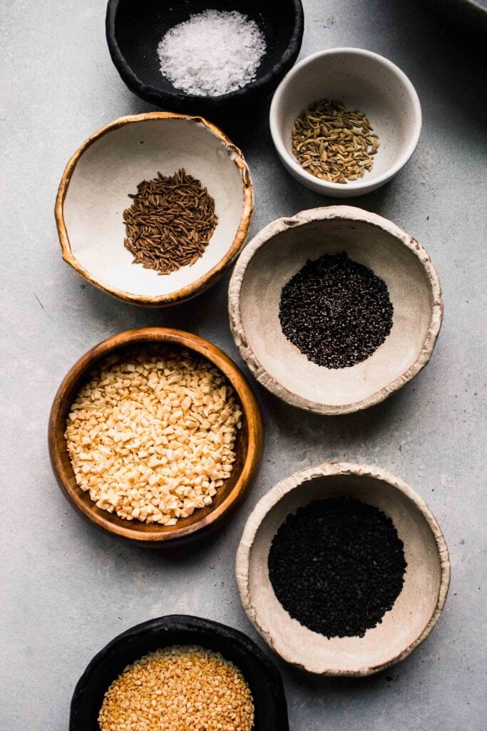 Small bowls of individual spices for bagel seasoning.
