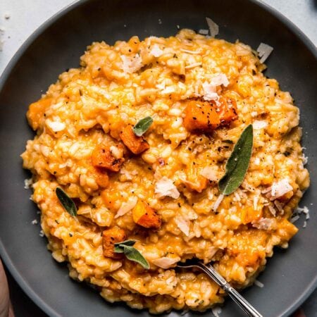 Overhead shot of hand holding bowl of butternut squash risotto.