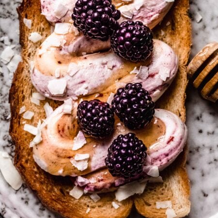 Overhead close up of ricotta toast next to honey wand.