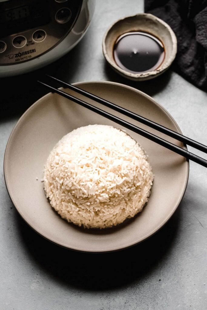 Side view of bowl of rice next to soy sauce.