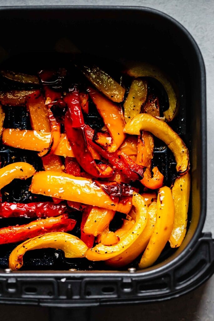 Cooked peppers in air fryer basket with a nice char.