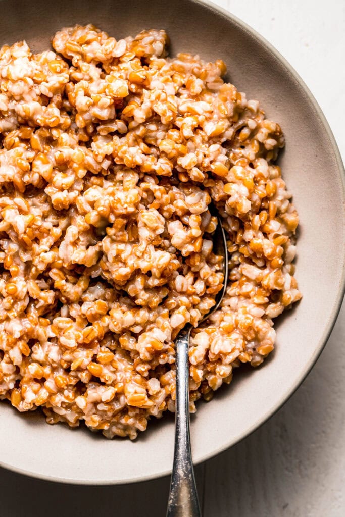 Overhead close up of cooked farro in serving bowl with spoon.