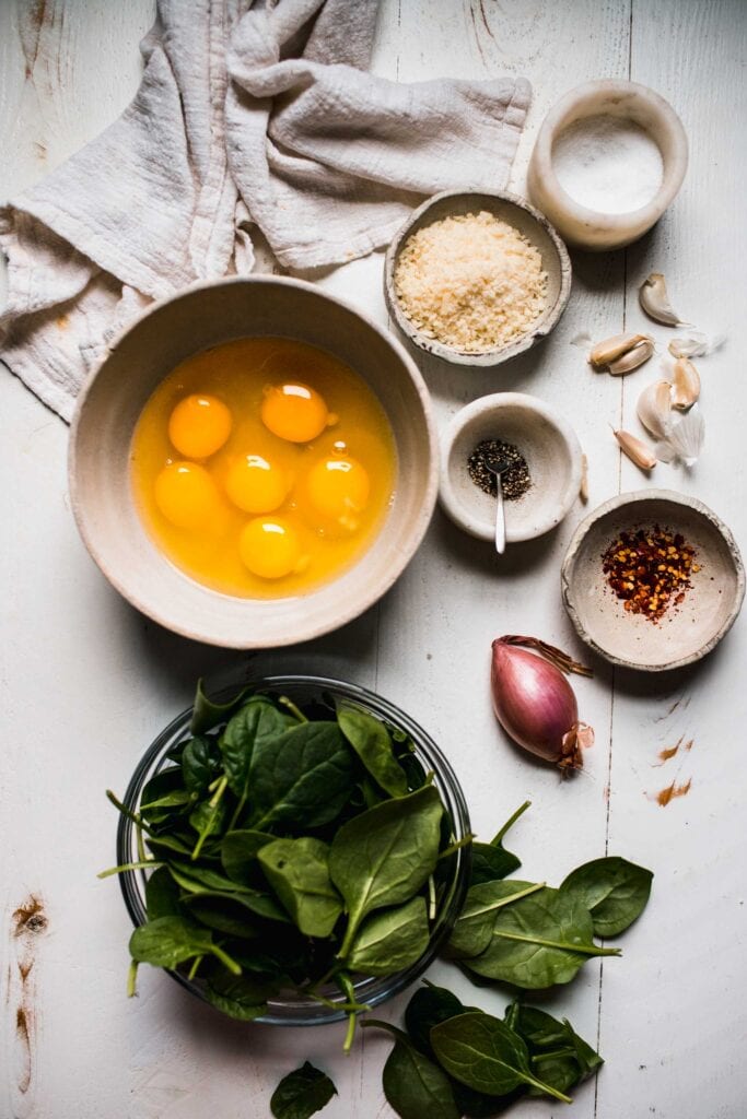 Ingredients for spinach and eggs on counter.