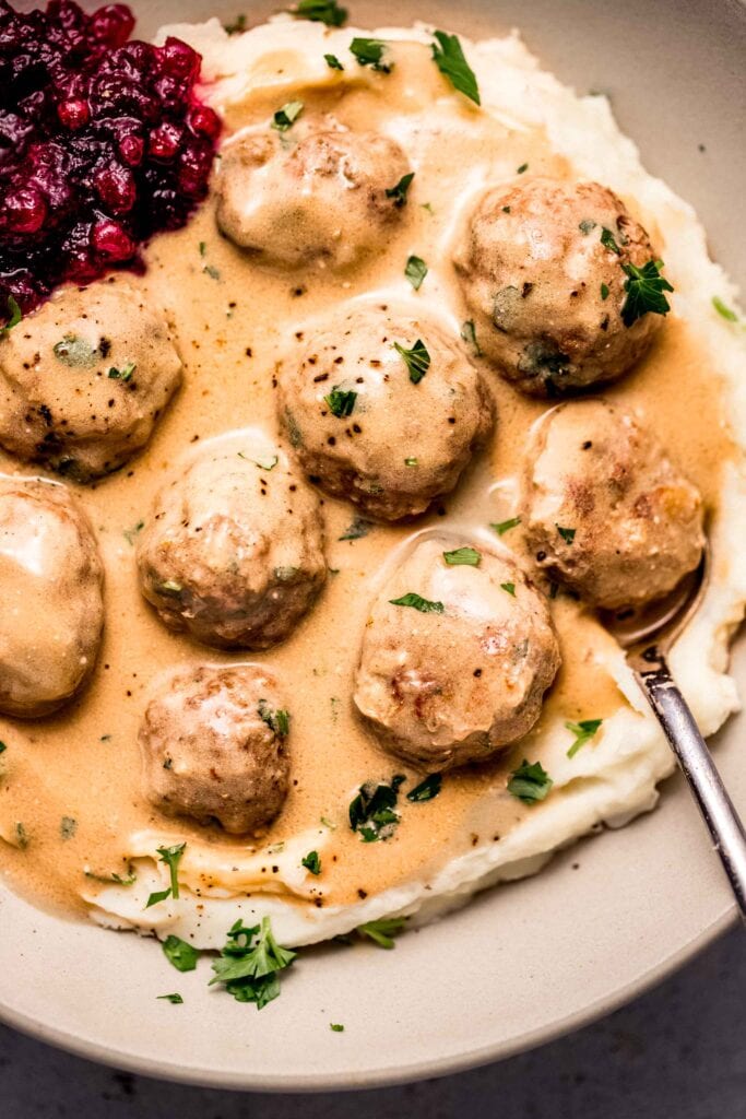 Overhead close up of plate of swedish meatballs on mashed potatoes.
