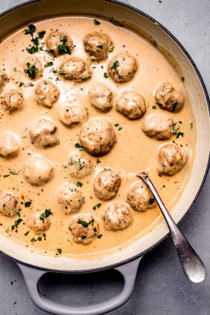 Overhead shot of meatballs bathing in skillet of swedish meatball sauce.