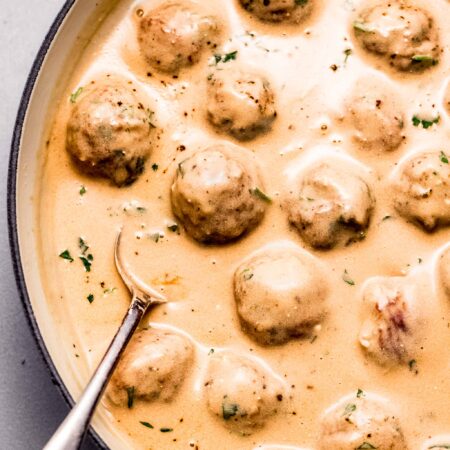 Swedish meatball sauce in large skillet with spoon.