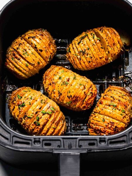 Cooked hasselback potatoes in air fryer basket.