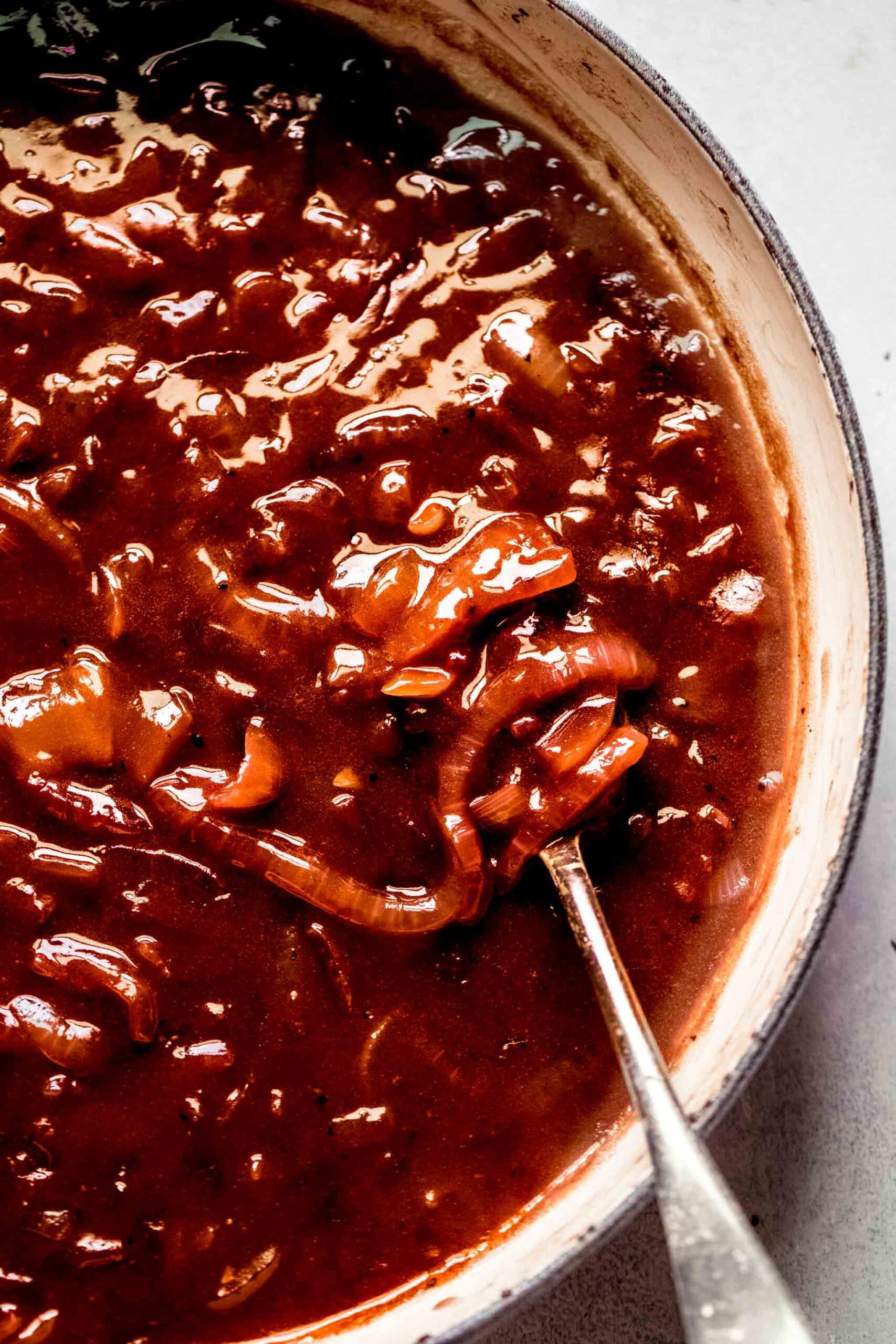 Onion gravy in large skillet with spoon.