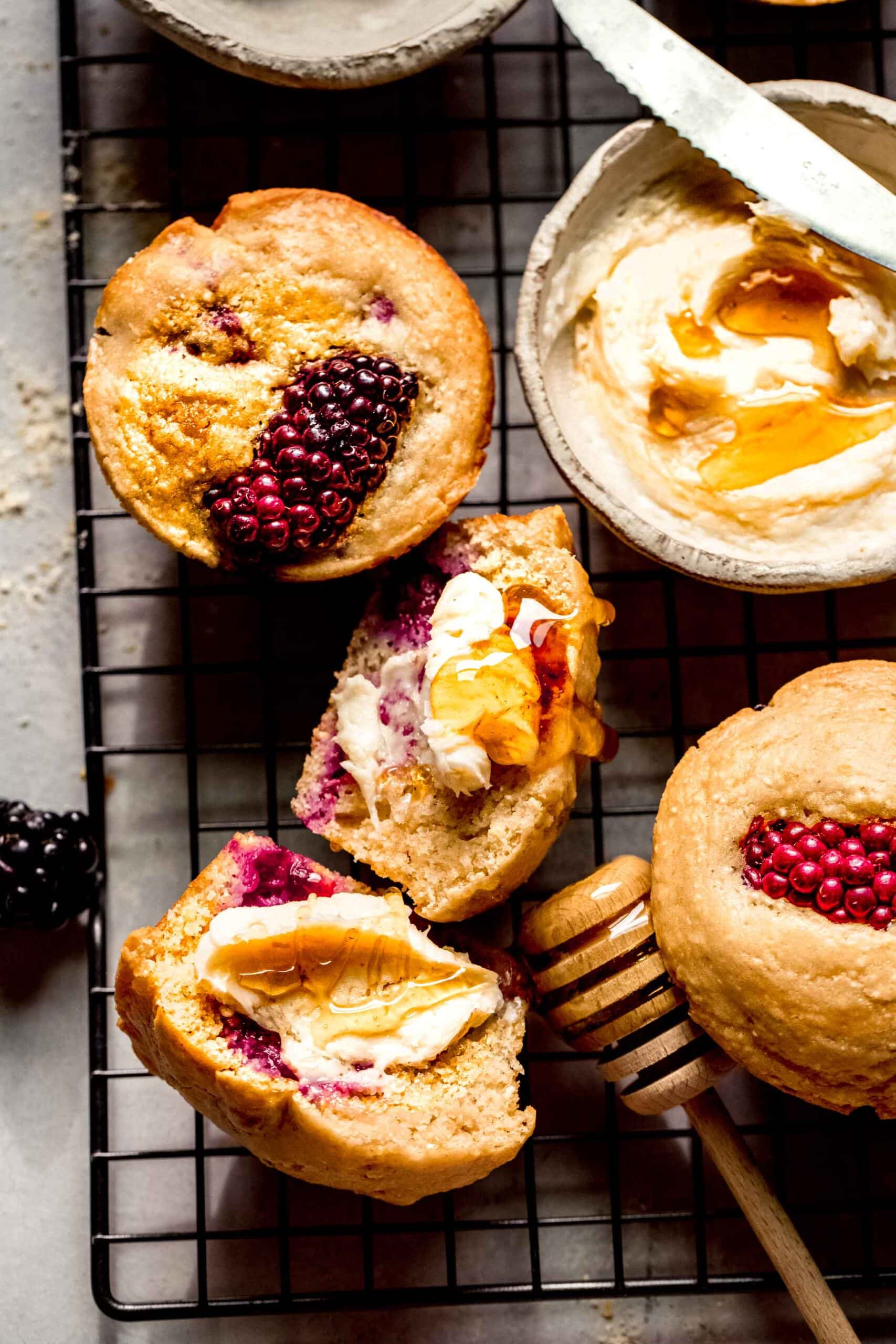 Blackberry cornbread muffins on cooling rack slathered with honey butter.