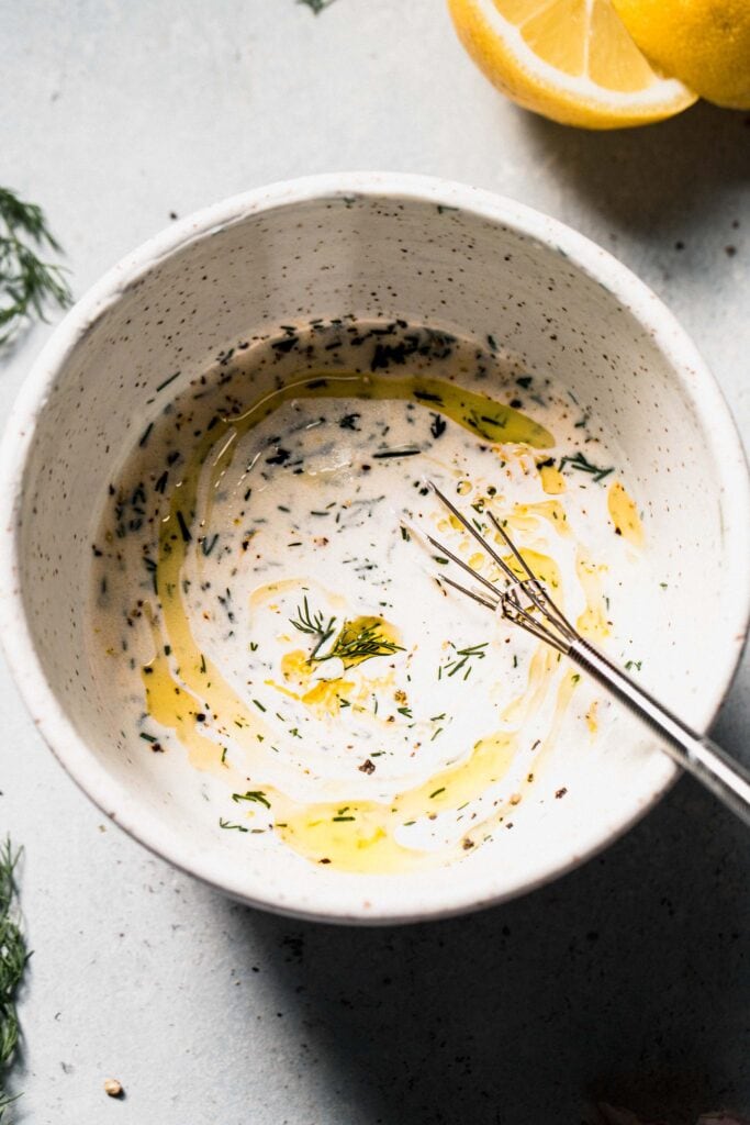 Bowl of creamy dill sauce with whisk.