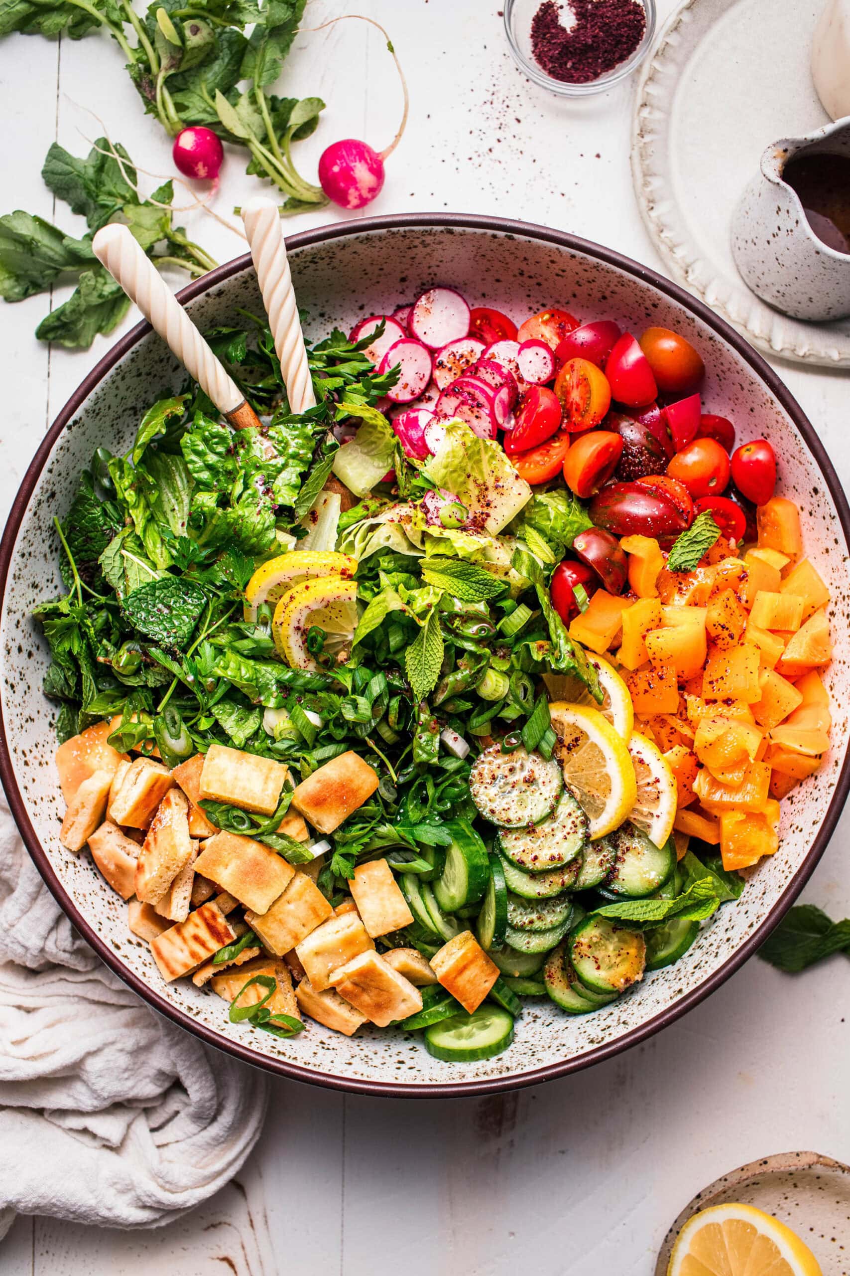 Fattoush salad assembled in large bowl with serving tongs.