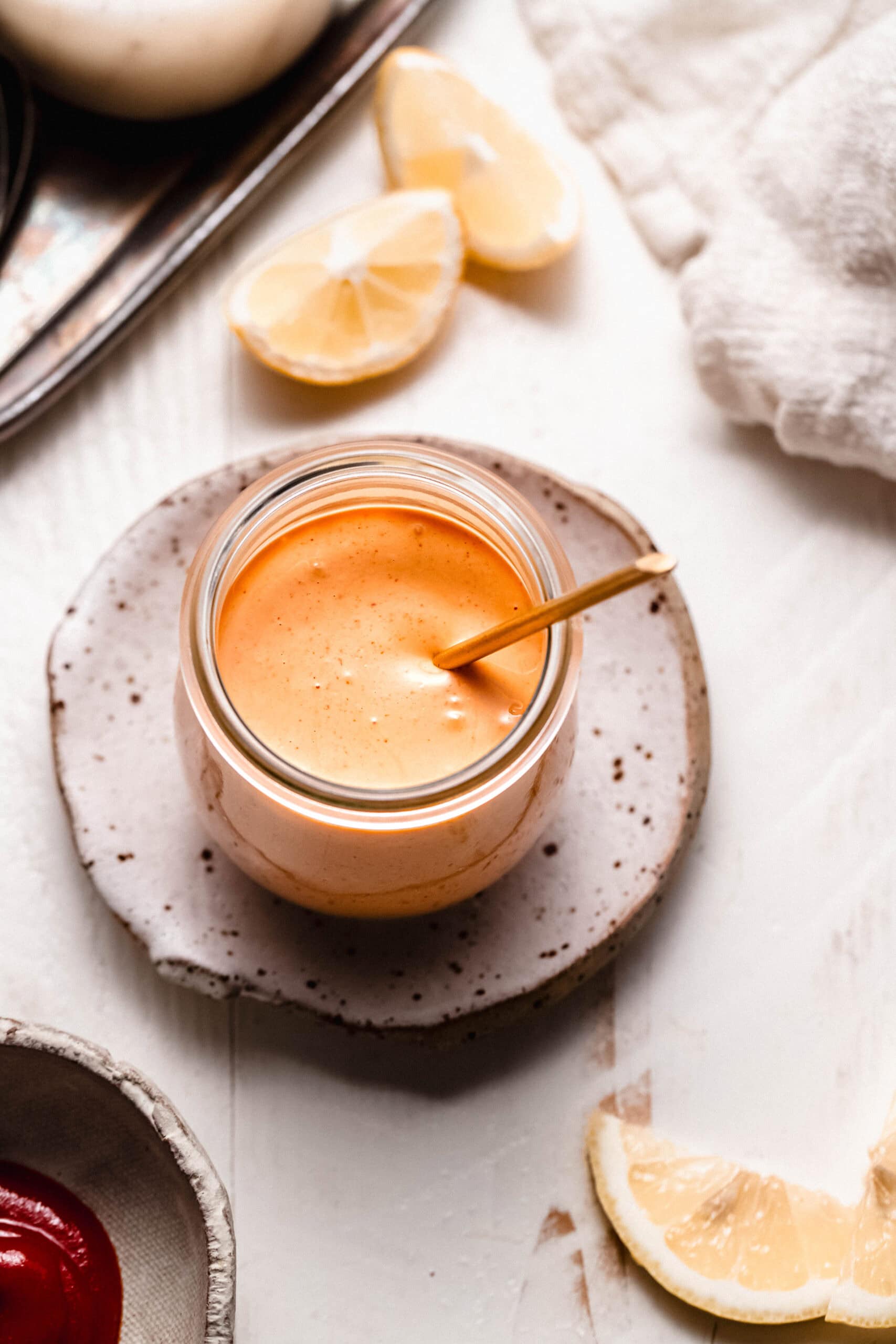 Sriracha mayo sauce in small glass jar with spoon.