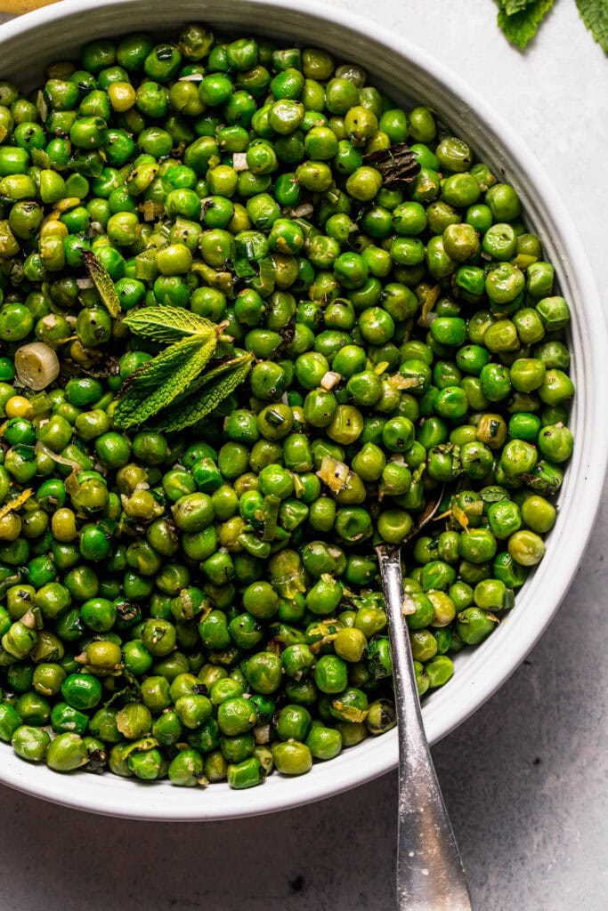 Overhead close up of mint peas in bowl with spoon.