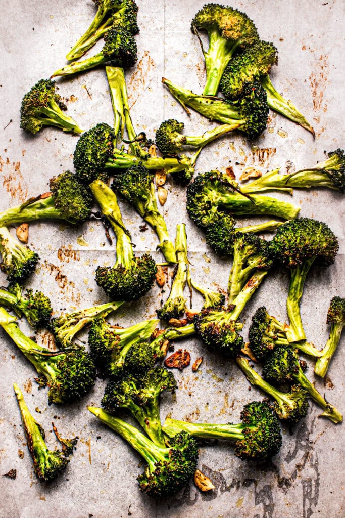 Roasted broccoli spears on baking sheet.